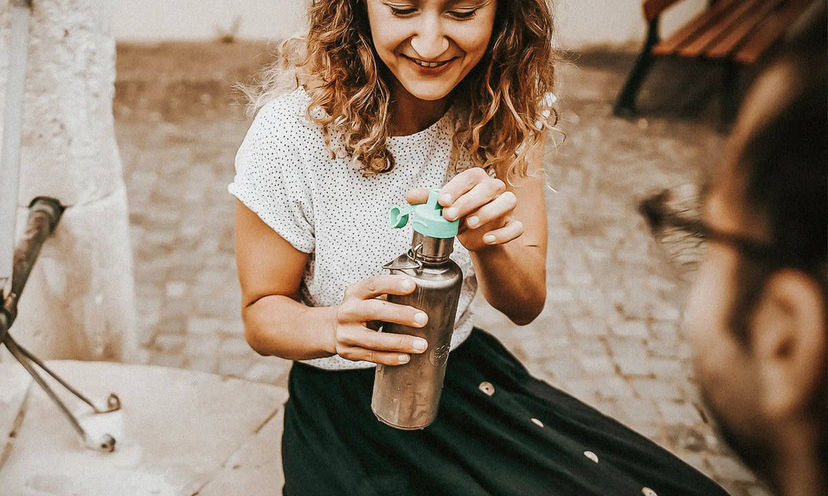 Frau mit Trinkflasche von soulbottles und Wasserfilter an öffentlichen Brunnen