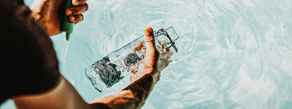 Mann mit Trinkflasche aus Glas füllt Flasche mit Brunnenwasser